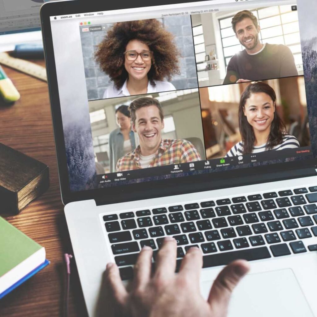 Videochamada aberta na tela de um notebook, com quatro participantes sorrindo
