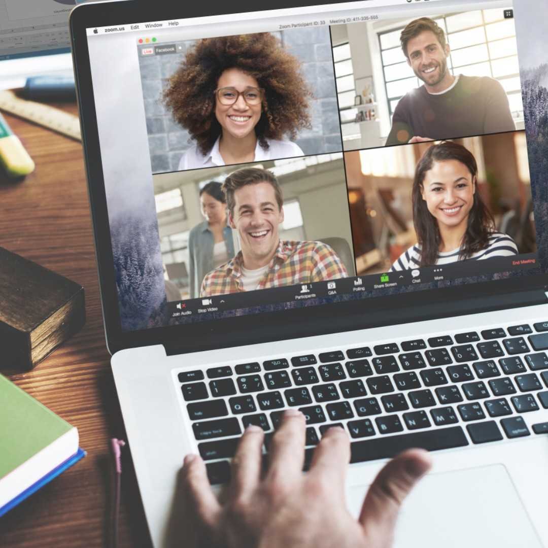 Videochamada aberta na tela de um notebook, com quatro participantes sorrindo