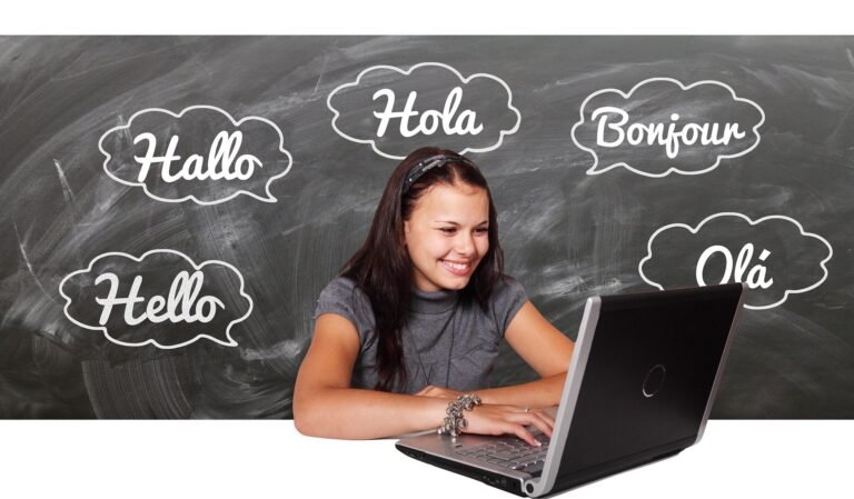 Jovem ao notebook diante de uma lousa com balões de saudação: Hallo, Hola, Bonjour, Hello e Olá