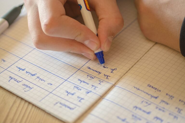 Mão escreve exercícios de um idioma estrangeiro em um caderno pautado